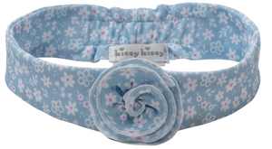 The Fall in Bloom Headband by Kissy Kissy is a light blue, stretchy baby headband featuring a floral pattern, a central fabric flower, and the signature brand label.