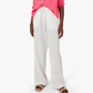 Someone styled in a pink top with Xirena's Dylan Pant, featuring white washed cotton gauze and an elastic drawstring waist, paired stylishly with sandals.