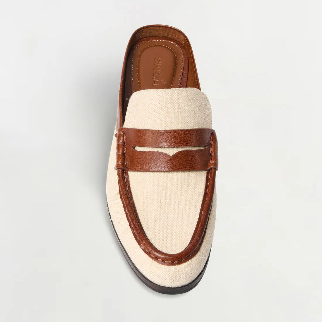 The Simkhai Dean Canvas Como Loafer Mule is shown from above, displaying its stylish slip-on design with a beige fabric upper and brown leather trim and details against a plain white background.