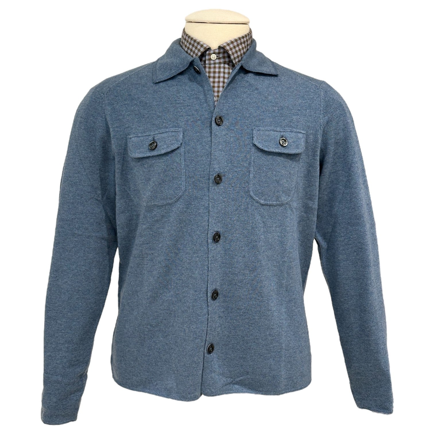 The Alan Paine Tore Cardigan with Pockets, shown on a mannequin over a checkered collared shirt, is a versatile blue layering piece featuring two breast pockets.