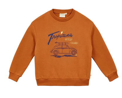The Arsene & Les Pipelettes Boys' Tropicana Sweatshirt is made from organic cotton fleece in a rust color, featuring "Tropicana Surf Camp" text and a blue outlined graphic of a car with a surfboard on the roof, shown against a white background.