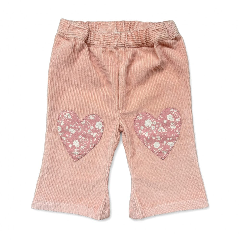The Louis Louise Baby Girls’ Holly Trouser in powder pink corduroy, designed for toddlers, features an elasticated waist and charming heart-shaped knee patches with floral details, shown on a white background.