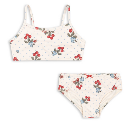 The Girls’ Frago Bikini by Konges Slojd is a two-piece swimsuit featuring thin straps and a cream background decorated with cherries, blue flowers, and polka dots. Crafted from soft, stretchy bikini fabric for all-day comfort, this charming style is finished with adorable bow details.