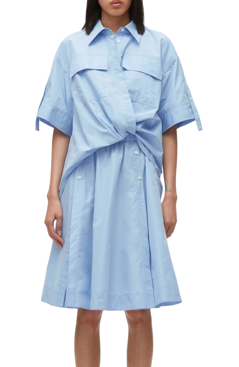 A person in a blue 3.1 Phillip Lim Tucked Front Shirt Dress with short sleeves and a tie waist, designed with an oversized fit.