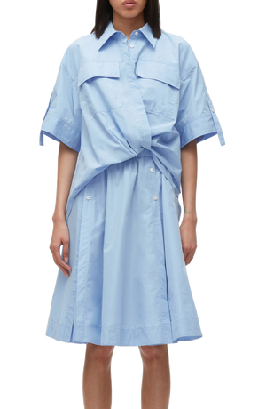 A person in a blue 3.1 Phillip Lim Tucked Front Shirt Dress with short sleeves and a tie waist, designed with an oversized fit.