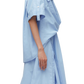 A side view of a person wearing a light blue, oversized 3.1 Phillip Lim Tucked Front Shirt Dress with a structured, layered design.