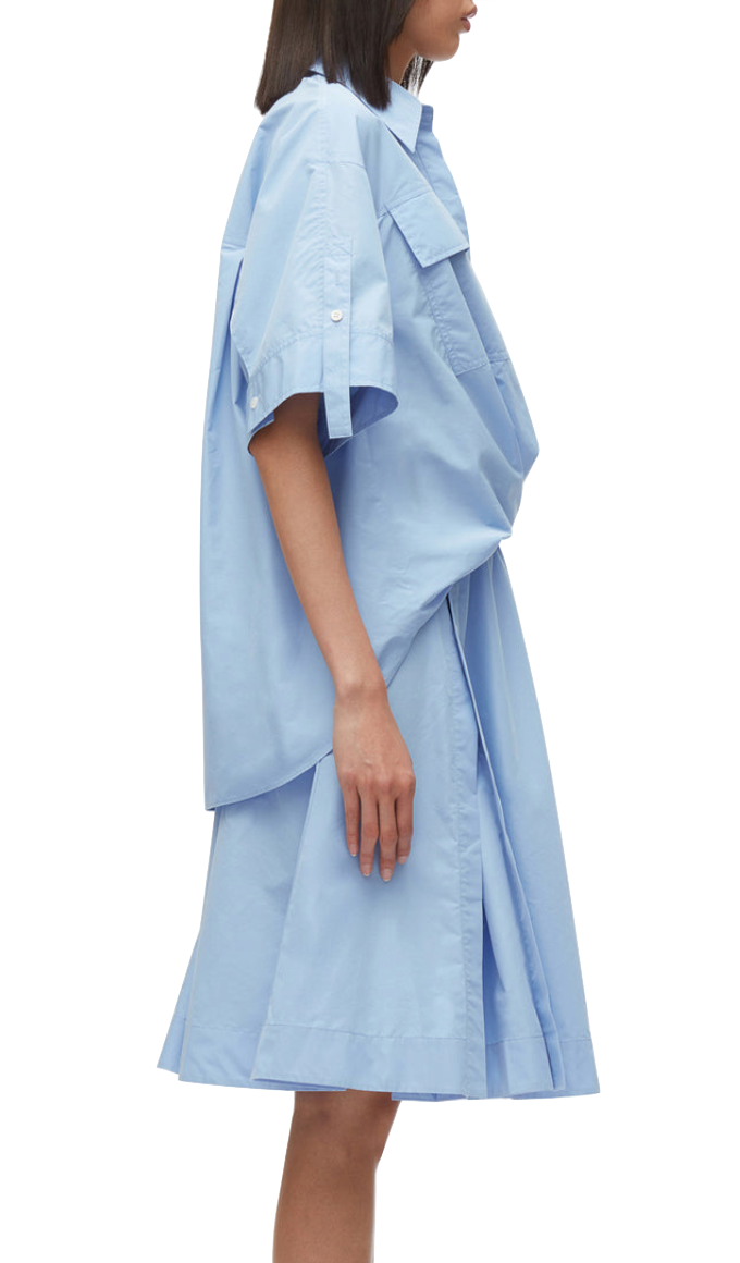 A side view of a person wearing a light blue, oversized 3.1 Phillip Lim Tucked Front Shirt Dress with a structured, layered design.