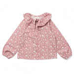 The Girls’ Angele Shirt by Louis Louise features a pink long-sleeve floral print with a white floral pattern, front buttons, ruffled collar, and tie detail—displayed on a white background, this charming tunic is expertly crafted for girls’ comfort and style.