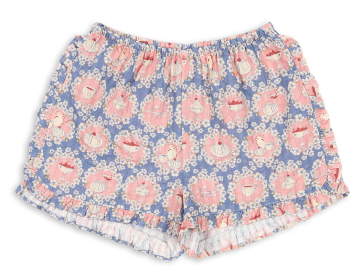 Introducing the Baby Girls’ and Girls’ Kim Frill Shorts by Konges Slojd—crafted from soft organic cotton, these blue and pink floral pajama shorts feature charming tea cup, teapot, and wreath prints. The elastic waist and ruffled hem add whimsical charm and comfort for delightful lounging.