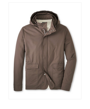 The Peter Millar Discovery Field Jacket is a brown hooded travel jacket in performance twill with front snap buttons, zipper closure, and two large pockets, shown against a white background.