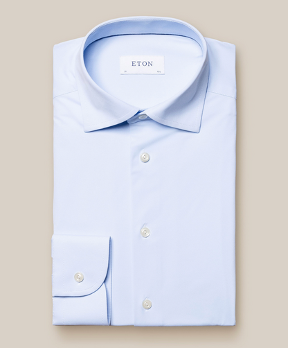 A light blue Four-Way Stretch Shirt by Eton, featuring a button-down front and collar for exceptional comfort, is neatly folded on a plain beige background.