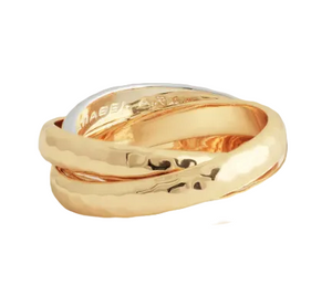 The Farrier Mixed Metal Triple Band Ring by Anabel Aram features three interlocking gold bands—one polished, two hammered—and an engraved inscription inside, making it a distinctive jewelry piece.