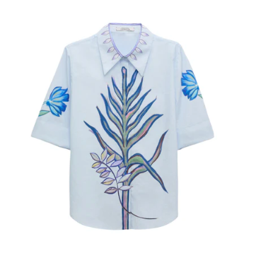 The Floral Embrace Blouse by Dorothee Schumacher is a light blue short-sleeve cotton-poplin top featuring a striking large botanical key print on the front and blue floral motifs on each sleeve.