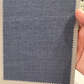 A hand holds a sample card displaying blue wool fabric for Samuelsohn Slim Fit Flat Front Wool Pants, featuring zigzag-cut edges and an unfinished hem against a light background.