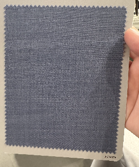 A hand holds a sample card displaying blue wool fabric for Samuelsohn Slim Fit Flat Front Wool Pants, featuring zigzag-cut edges and an unfinished hem against a light background.