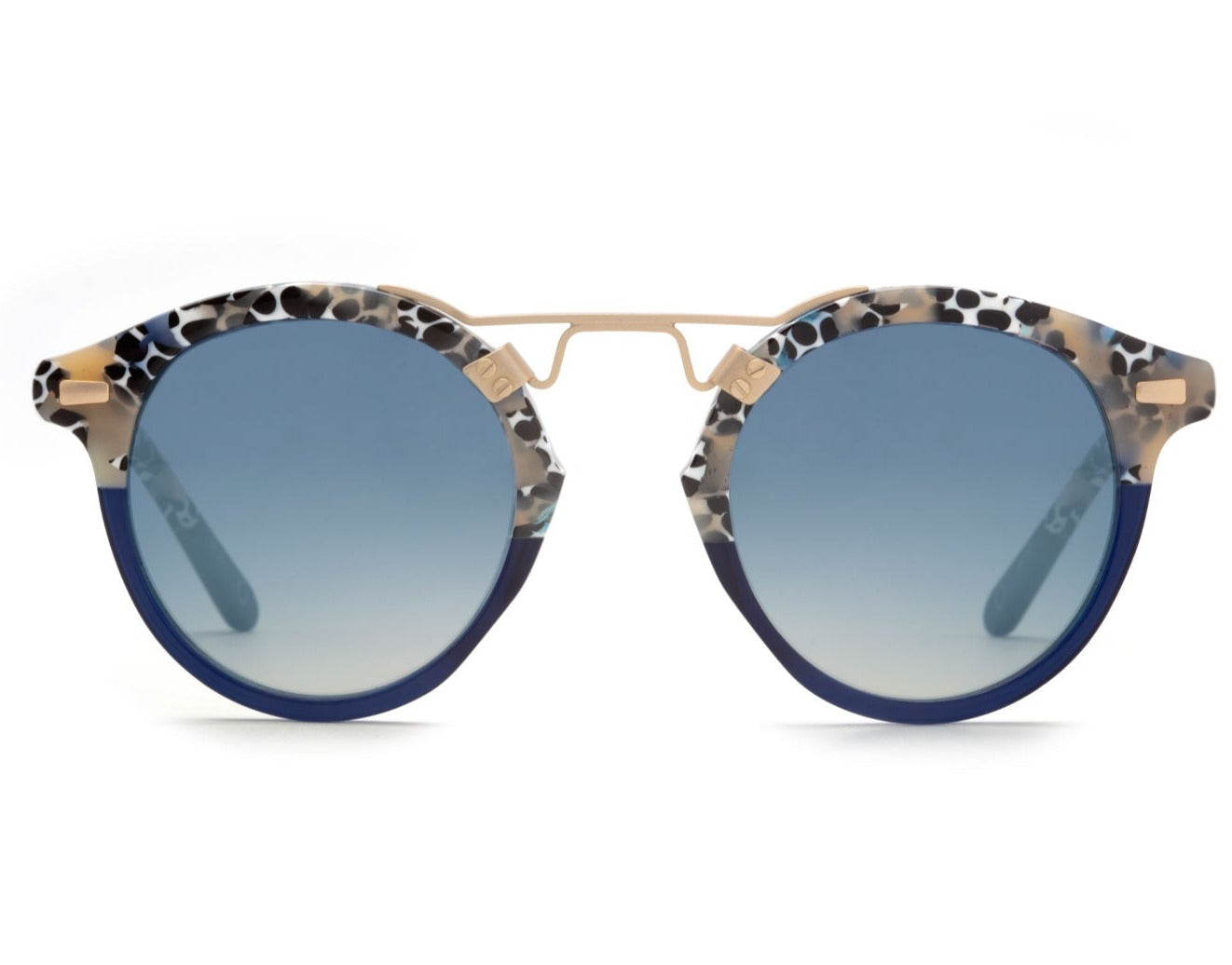 The Krewe St Louis Mirrored Sunglasses feature round lenses with a blue gradient tint and a 24K gold plated bridge. The luxury acetate frames are adorned with a black, white, and beige speckled pattern, offering stylish looks along with UVA/UVB protection.