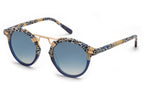 Introducing the Krewe St Louis Mirrored Sunglasses by Krewe: Luxury acetate sunglasses boasting blue gradient lenses, a chic spotted black, white, and beige frame, and 24K gold-plated hardware on the bridge for an elegant touch. Experience both style and unparalleled UVA/UVB protection with every wear.