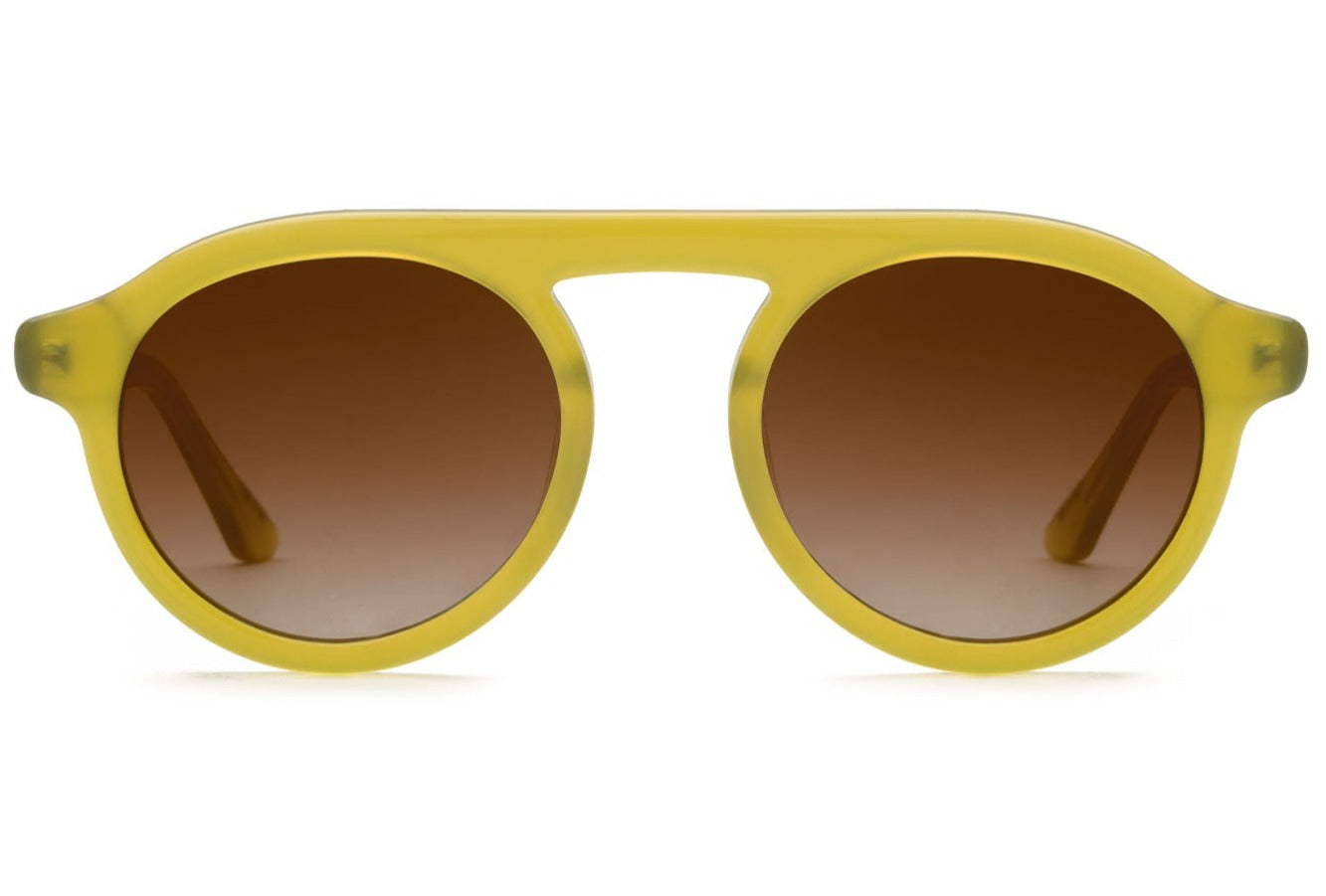 The Krewe Cameron Sunglasses showcase a trendy yellow round acetate frame with brown gradient lenses, providing excellent UVA and UVB protection against a simple white backdrop.