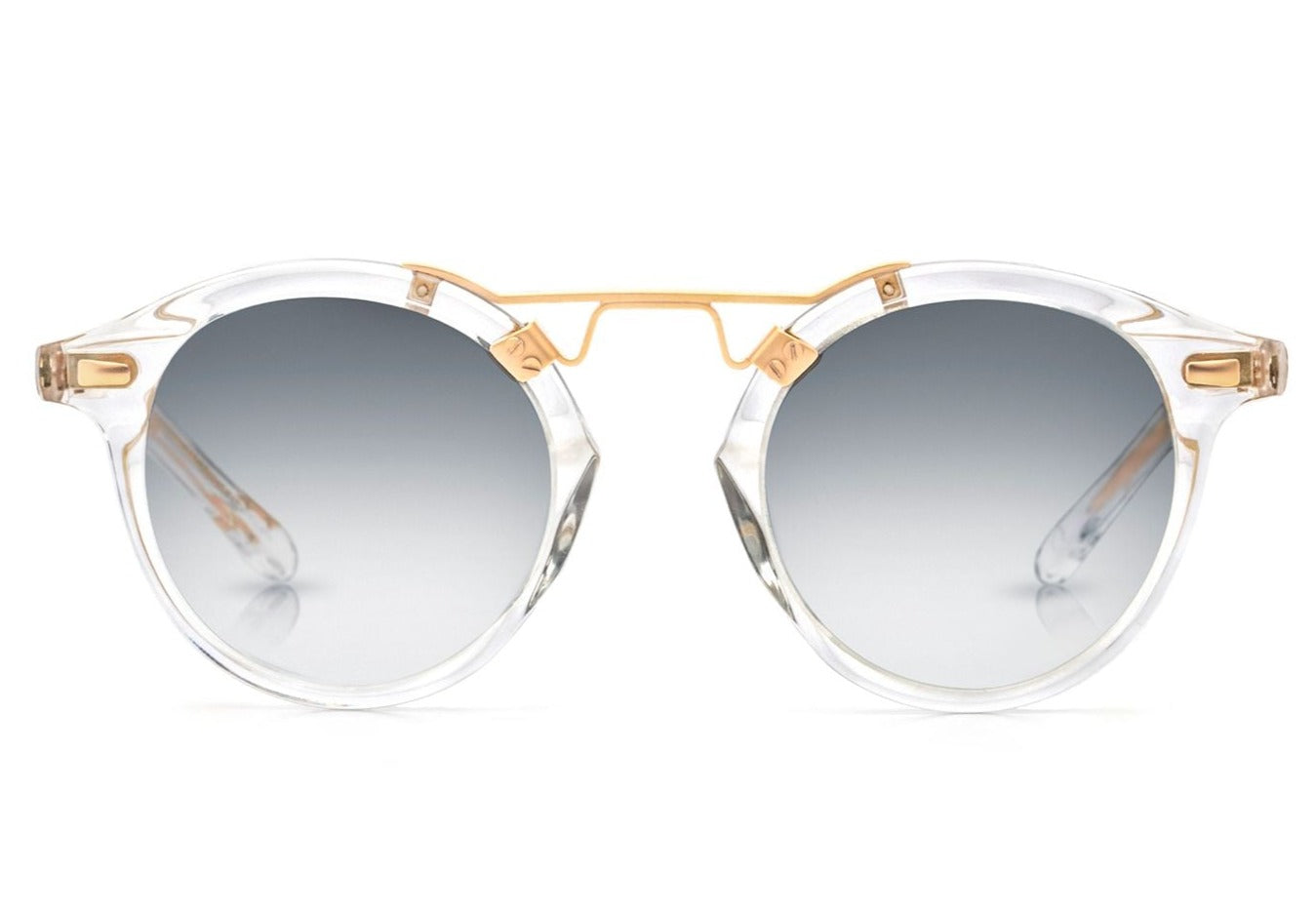 Introducing the Krewe St Louis Mirrored Sunglasses: a luxurious pair of round acetate sunglasses featuring clear frames, gradient grey lenses, and 24K gold plated detailing on the bridge and temples. These stylish sunglasses offer impeccable fashion alongside exceptional UVA / UVB protection.