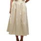Someone is wearing the Simkhai Elora Midi Skirt, a cream-colored, high-waisted pleated skirt, paired with a matching short-sleeve top and white heeled sandals.