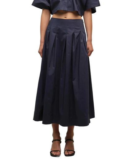 A person wearing the Simkhai Elora Midi Skirt with a matching cropped top and black heeled sandals, standing against a white background.