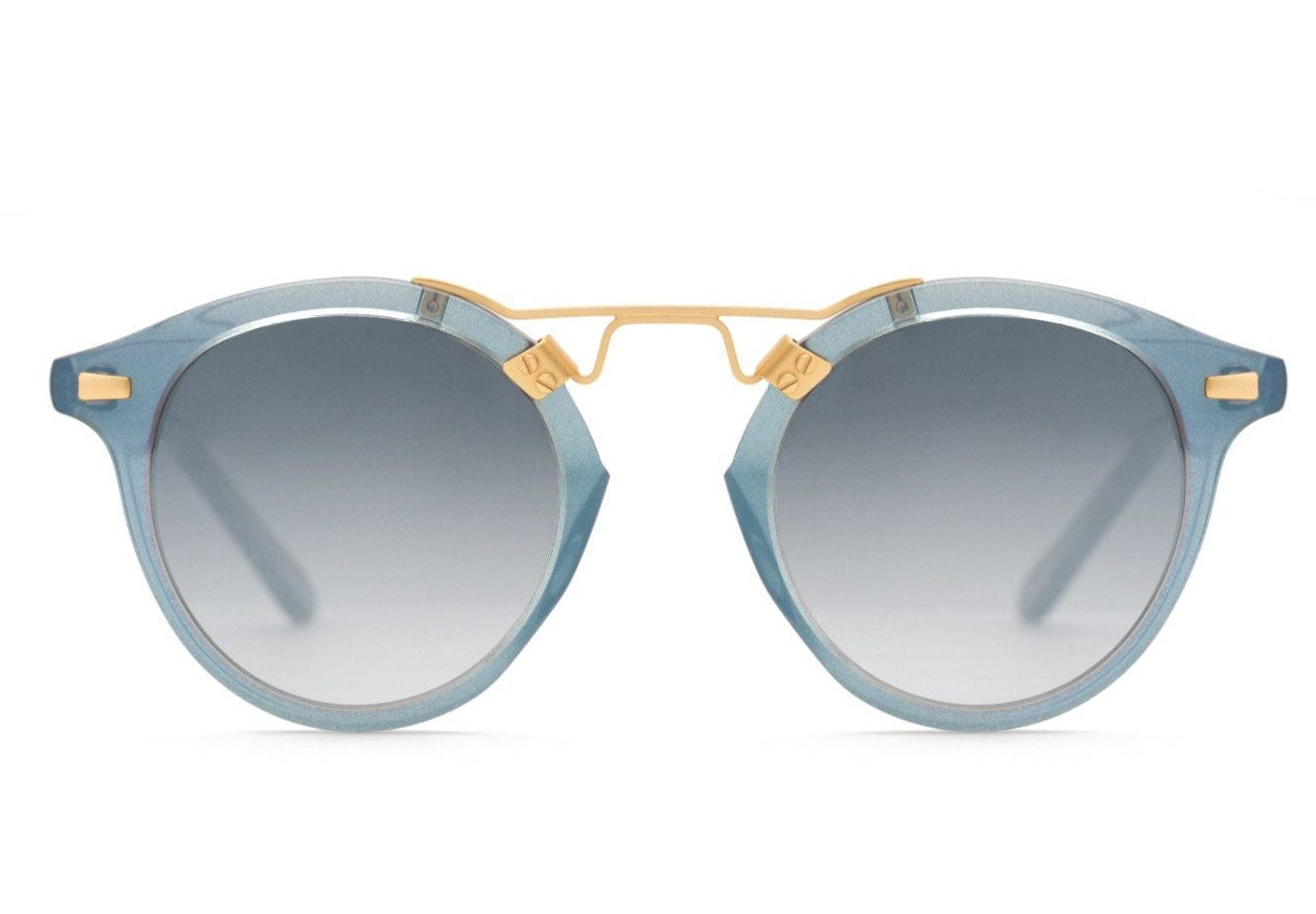 Front view of Krewe St Louis Mirrored Sunglasses by Krewe, featuring luxury acetate round blue frames, a 24K gold plated nose bridge, and gradient lenses that offer UVA / UVB protection, displayed on a white background.