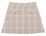 Girls’ Perrin Pocket Flannel Skirt by The Beaufort Bonnet Company, showcasing a beige A-line silhouette with a white Thompson Park Plaid pattern, two front flap pockets, and elegant gold button details.