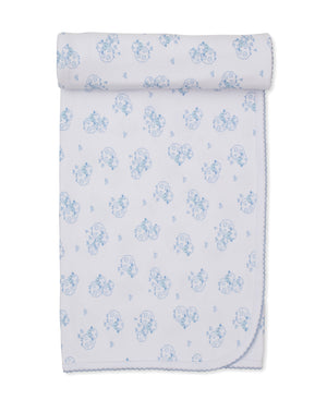 The Sweet Sheep Blanket by Kissy Kissy is a white baby blanket adorned with light blue cartoon animals and sheep, crafted from soft Pima cotton with scalloped edging and neatly rolled at one end.