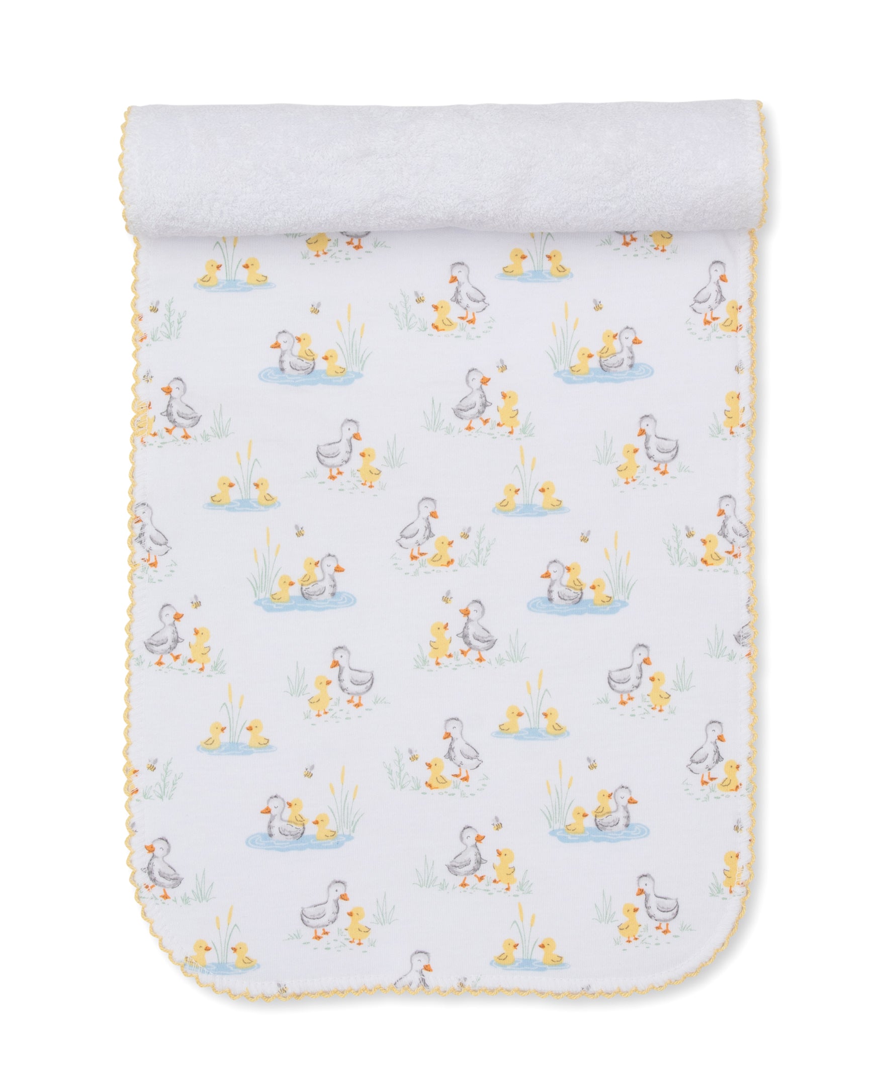 Introducing the Duck Pond Paddles Burp Cloth by Kissy Kissy—a white Pima cotton cloth edged in yellow, adorned with a charming repeating print of ducks and ducklings among ponds and grass. Soft and comfortable, it is rolled at the top and displayed flat on a white background, making it ideal for gentle burping or as a cozy companion to your favorite baby blankets.
