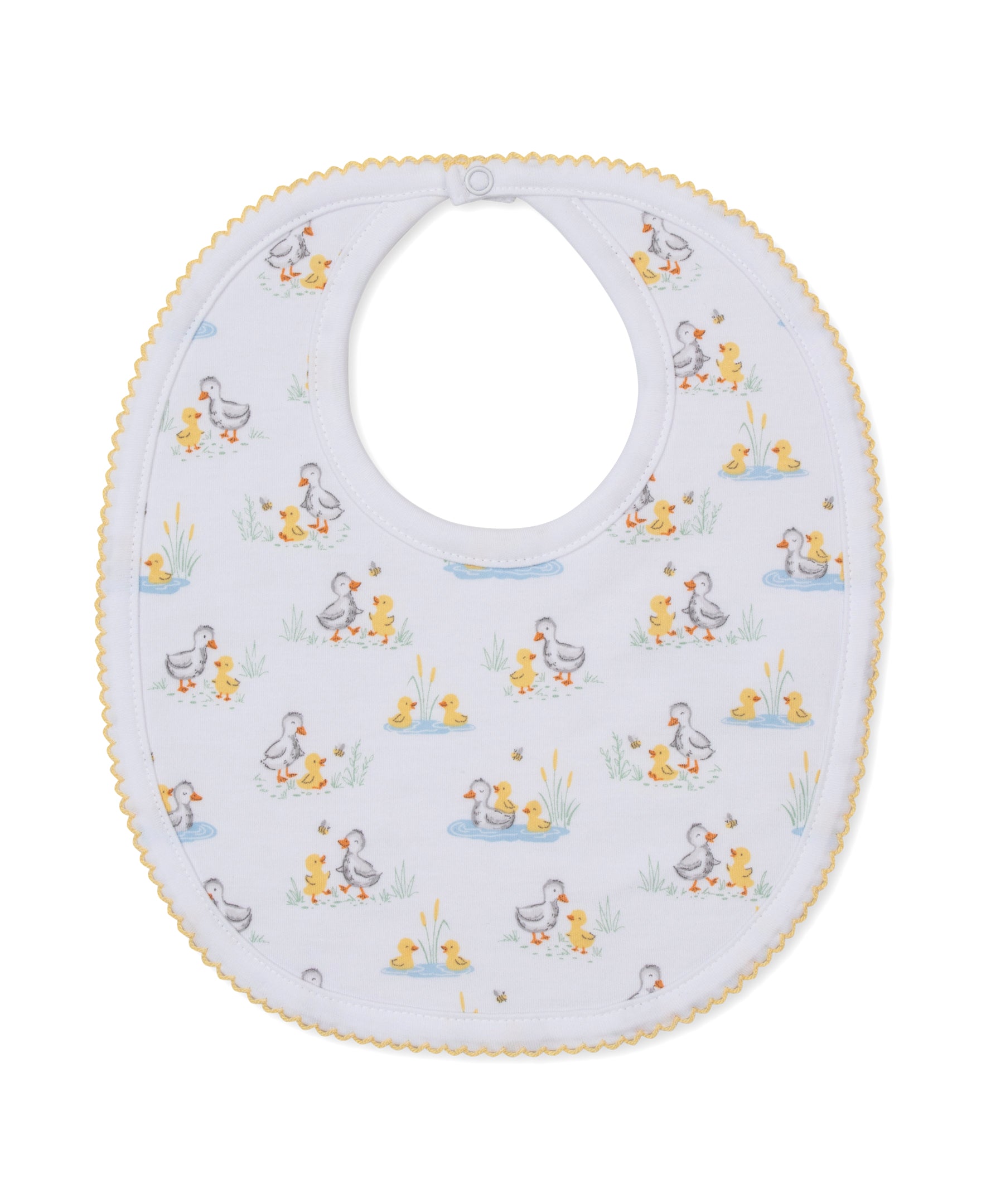 The Duck Pond Paddles Bib by Kissy Kissy is a white baby bib with yellow scalloped trim, crafted from the softest Pima cotton for ultimate comfort and adorned with a playful duck and duckling print among grass and water scenes.