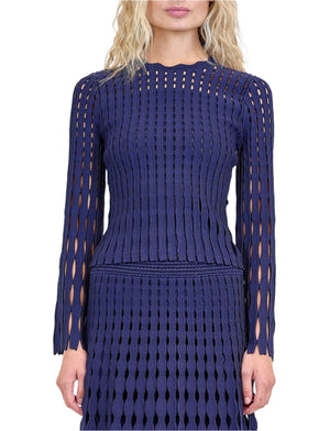 Woman in a long-sleeve, dark blue Simkhai Peyton Top with vertical cut-out pointelle knit, paired with the matching Wilma skirt; face partially out of frame.