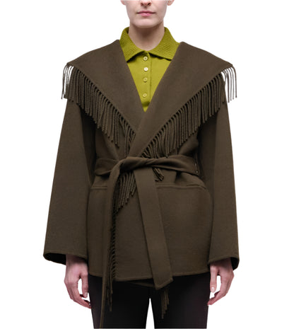A person models the Simkhai Rowen Fringe Jacket, a dark brown Western-style belted coat with fringe on the shoulders and front, worn over an olive green collared shirt against a white background.