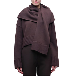 A person wears the Simkhai Elson Scarf Sweater—dark brown with a matching attached scarf, ribbed cuffs, and hem—standing against a plain white background.