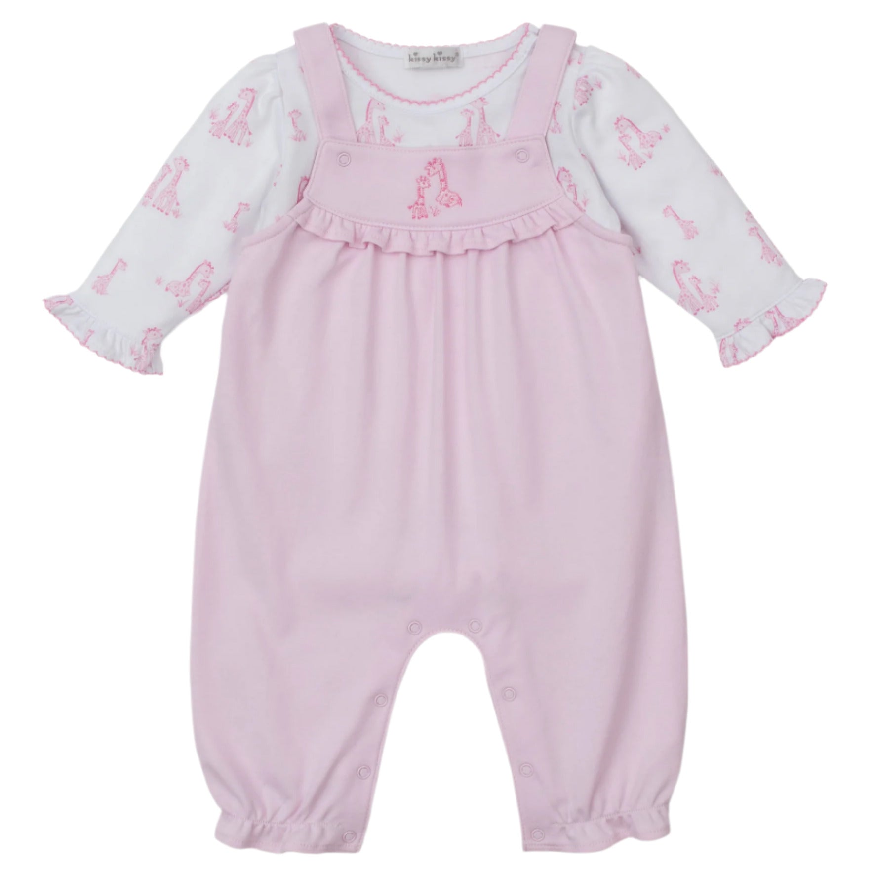 The Kissy Kissy Baby's Giraffe Grace Overall Set features pink overalls with ruffled straps and a giraffe print long-sleeve shirt, plus snap buttons at the legs and a chest ruffle detail.