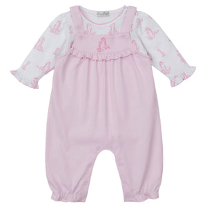 The Kissy Kissy Baby's Giraffe Grace Overall Set features pink overalls with ruffled straps and a giraffe print long-sleeve shirt, plus snap buttons at the legs and a chest ruffle detail.