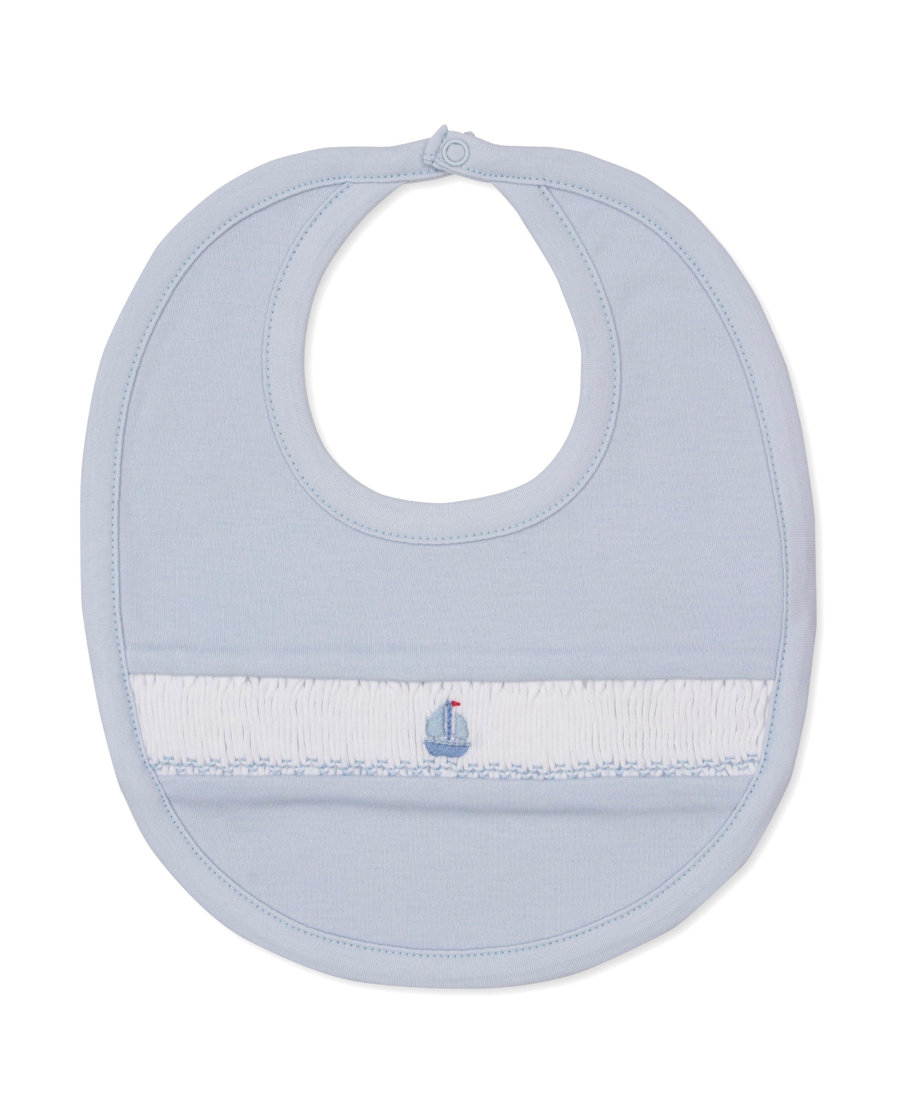 The CLB Summer Medley Smocked Bib by Kissy Kissy is a light blue baby bib made from soft Pima cotton, featuring a hand-smocked white band with a delicate sailboat embroidery at the center and finished with a secure button closure at the neck.