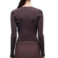 A woman with long brown hair in a ponytail is shown from the back wearing the Simkhai Ailany Cardigan, a ribbed knit, button-front style, paired with a matching skirt.