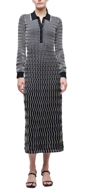 A person wears the Kassidy Polo Midi Dress by Simkhai—a long sleeve dress featuring a white wavy line pattern, black collar, and buttoned neckline—paired with black sandals.