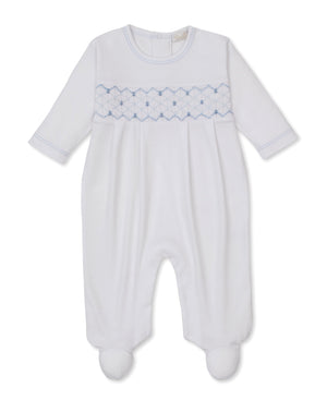 Kissy Kissy Baby Boys' Hand Smocked Footie, crafted from soft white Pima cotton, features delicate blue hand smocking across the chest, a round neckline, and cozy footed legs, shown against a plain background.