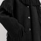 Close-up of Toteme's Fringed Scarf Jacket in black wool-blend bouclé, featuring fringe on the shoulders and sleeves, visible buttons, and a hand in the front pocket.