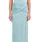 A woman wears the Simkhai Vienna Midi Skirt—a light blue, soft drape, figure-flattering piece—paired with beige sandals, standing against a white background.