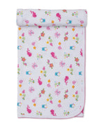 The Kissy Kissy Ocean Antics Blanket is a folded white baby blanket with a charming pink scalloped edge, adorned with a colorful undersea print featuring cartoon whales, octopuses, turtles, fish, and starfish on a white background. Crafted from ultra-soft Pima cotton, this cozy blanket offers gentle comfort for your little one.