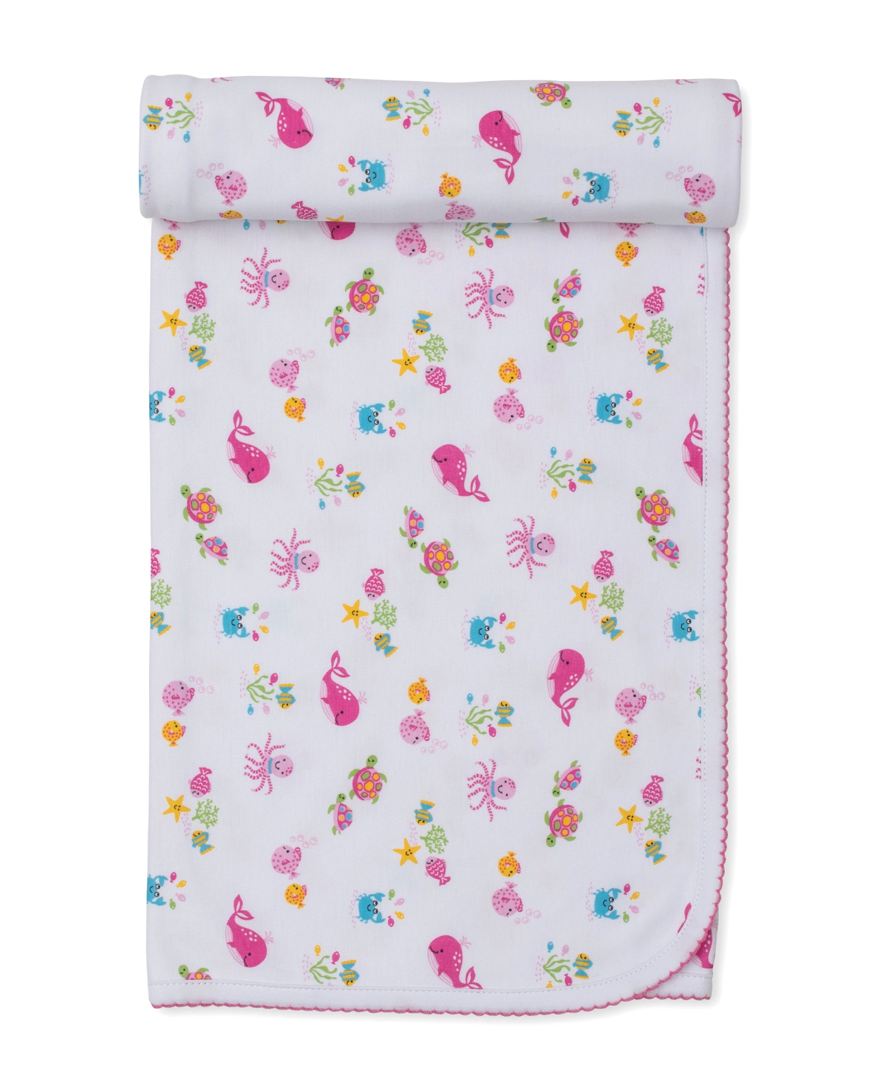 The Kissy Kissy Ocean Antics Blanket is a folded white baby blanket with a charming pink scalloped edge, adorned with a colorful undersea print featuring cartoon whales, octopuses, turtles, fish, and starfish on a white background. Crafted from ultra-soft Pima cotton, this cozy blanket offers gentle comfort for your little one.