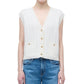 A person wearing the Simkhai Perrie Vest, a sleeveless white cable-knit cashmere V-neck with two front pockets, paired with blue jeans.