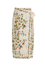 The Luna Midi Pareo by Agua By Aguabendita is a white skirt with a colorful floral and fruit print, featuring a chic tie waist closure.