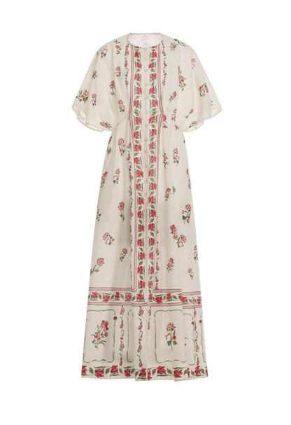 The Gesto Dress by Agua By Aguabendita is a long cream linen kaftan with wide short sleeves, featuring pink and green floral patterns and geometric borders on the front, hem, and sleeves.