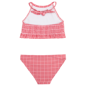 The Minnow Girls' Malibu Poppy Gingham Smocked Halter Bikini features a red and white gingham pattern, a ruffled smocked crop top with a bow, and matching swim bottoms, displayed flat on a white background.