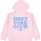 The Girls’ Hadley Cozy Hoodie by Feather 4 Arrow is a pink hooded sweatshirt made from ultra-soft, cozy fabric, featuring “COZY VIBE CLUB” and a heart printed in large blue letters on the back.