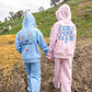 Two children stroll hand in hand outdoors, each bundled up in a plush Feather 4 Arrow hoodie that guarantees comfort on every outing. One wears the Girls’ Hadley Bestie Hoody with “BESTIE” proudly displayed, while the other sports a “COZY VIBE CLUB” design. The path beneath them is cracked and scattered with straw.