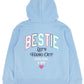Stay cozy in the Girls’ Hadley Bestie Hoody by Feather 4 Arrow—a light blue, ultra-soft sweatshirt with a hood, featuring “BESTIE Let’s Hang Out, Love You, K Bye” and a small red heart on the back in colorful lettering. Perfect for showing your bestie some love in comfort and style.